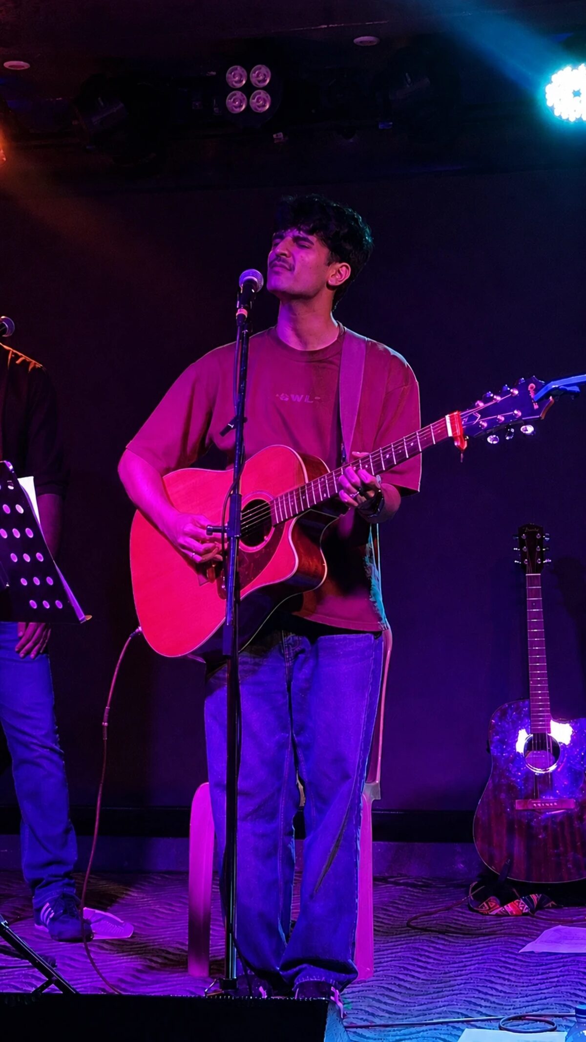Anurag singing on stage with an acoustic guitar